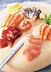 Sashimi with wasabi and lemon slices on wooden board