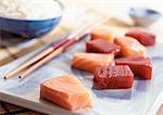 Sashimi on plate with chopsticks, bowl of rice in background, close-up