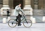 Mann trägt Anzug, Betriebs-Handy zum Ohr und Reiten Fahrrad, verschwommen.