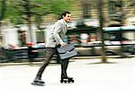Businessman rollerblading in park, blurred.