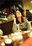 Young woman sitting in cafe, smoking a cigarette.