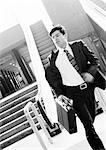 Businessman hurrying away from escalator, holding briefcase, blurred motion, b&w.