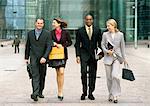 Group of business people walking together outside, full length, front view