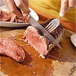 Close-up of hands cutting roast beef