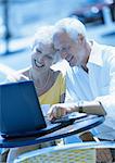 Mature woman and man sitting at a cafe terrasse with laptop computer