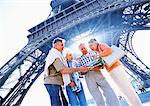 France, Paris, group of mature tourists examining a map in front of Eiffel Tower, low angle view