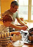 Child mixing batter with electric mixer, man holding saucepan