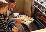 Man and child putting casserole in oven