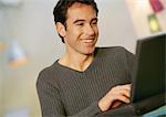 Man using laptop computer, smiling, close-up