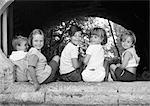 Five children sitting under an arch, b&w