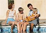 Séance familiale jeune ensemble, pieds dans la piscine (vue frontale).