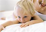 Woman and baby lying on bed, close-up, cropped