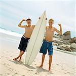 Two boys on beach holding surfboard