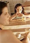 Girl eating at table with mother