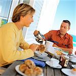 Teenage boy and father having breakfast outside