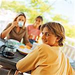 Teenage boy at table looking over shoulder, with family, portrait