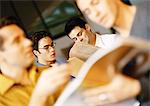 Men in office, looking at documents, blurred