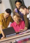 Two men and two women using laptop computer