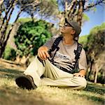 Man sitting on grass in forest, looking up