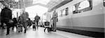 People on platform next to train, b&w, panoramic view