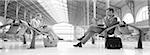 Businesspeople sitting in train station, b&w, panoramic view