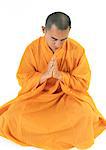 Buddhist monk sitting, meditating with hands together, high angle view