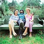 Mature man sitting between two women on bench