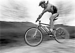 Man cycling, mid-air, blurred, b&w.