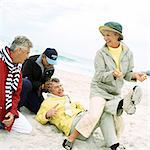 Mature group playing on beach, woman pulling man's laces