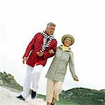 Couple d'âge mûr marche bras à bras sur la plage