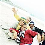 Groupe mature assis sur la plage à la recherche dans la caméra