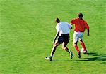 Two soccer players running for ball, full length