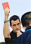 Referee showing red card in soccer match, portrait.