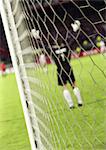 Goal keeper with arms up, rear view, blurred, seen from behind the net.