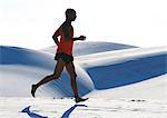 Barefooted man, running across dune, side view