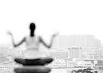 Woman sitting in yoga position, overlooking city, rear view, blurred, focus on background, b&w