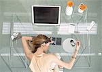 Woman leaning head on desk with futuristic devices, high angle view
