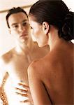 Nude couple facing each other through glass shower door, close-up