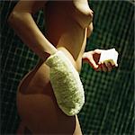 Nude woman with wash glove and soap, mid-section