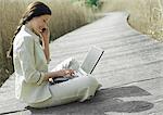 Businesswoman sitting with laptop computer, outdoors