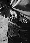 Hand taking gun from back of pants, close-up, b&w