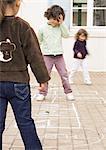 Three children playing hopscotch