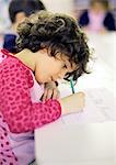 Child in classroom, writing, side view