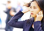 Businesswoman using cell phone, head and shoulders, close-up, blurred  background