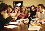 Group of young people sitting at table, having dinner together