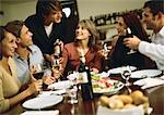 Group of young people around table, drinking wine