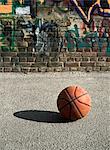 Basketball on ground next to graffitied wall