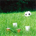 Paper cups in grass, soccer ball in background