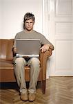 Man sitting on sofa, using laptop computer