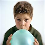 Boy blowing up balloon, portrait